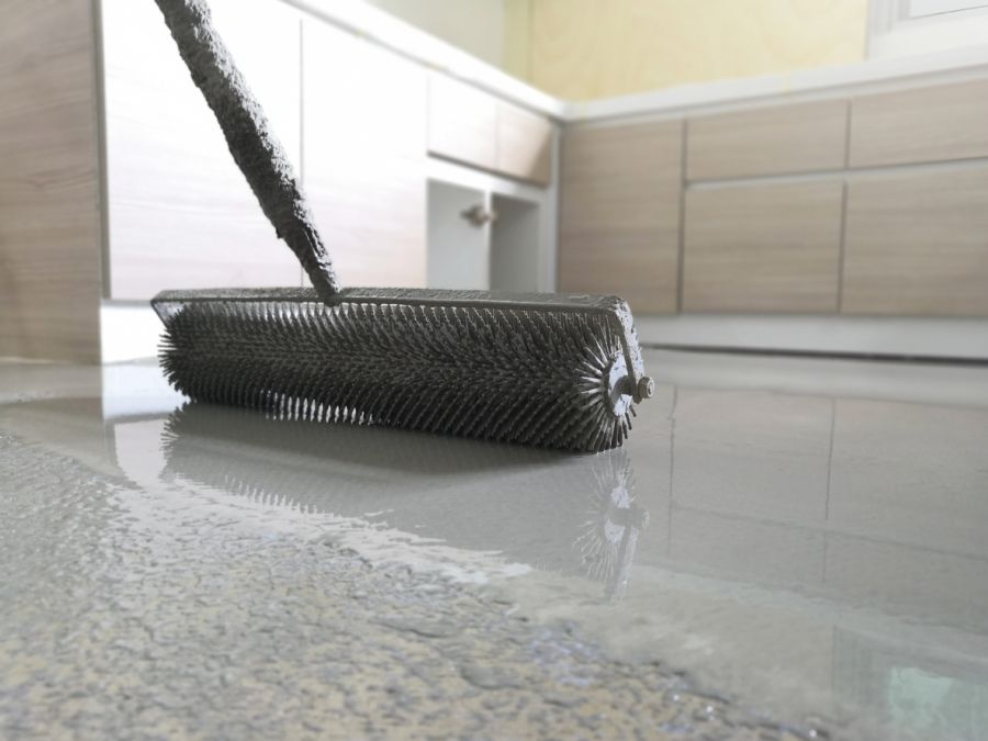 Roller applying non-slip coating on a glossy floor in a modern interior