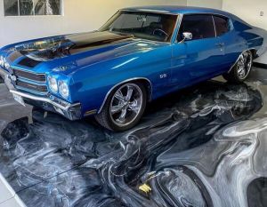 Blue classic muscle car parked on a black-and-white epoxy garage floor in a clean garage